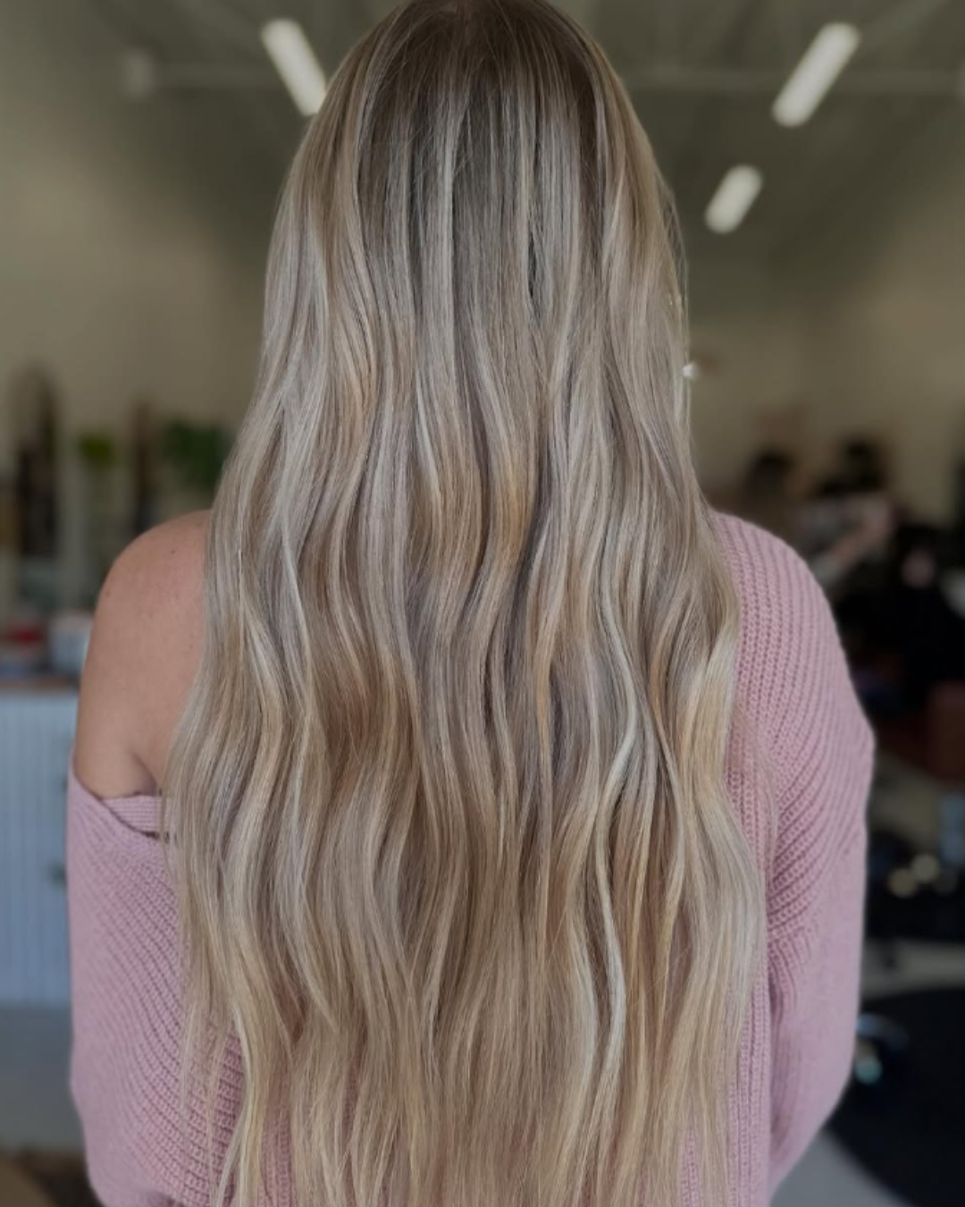 Long blonde wavy hair featuring two rows of 24-inch hair extensions installed by Abigail.