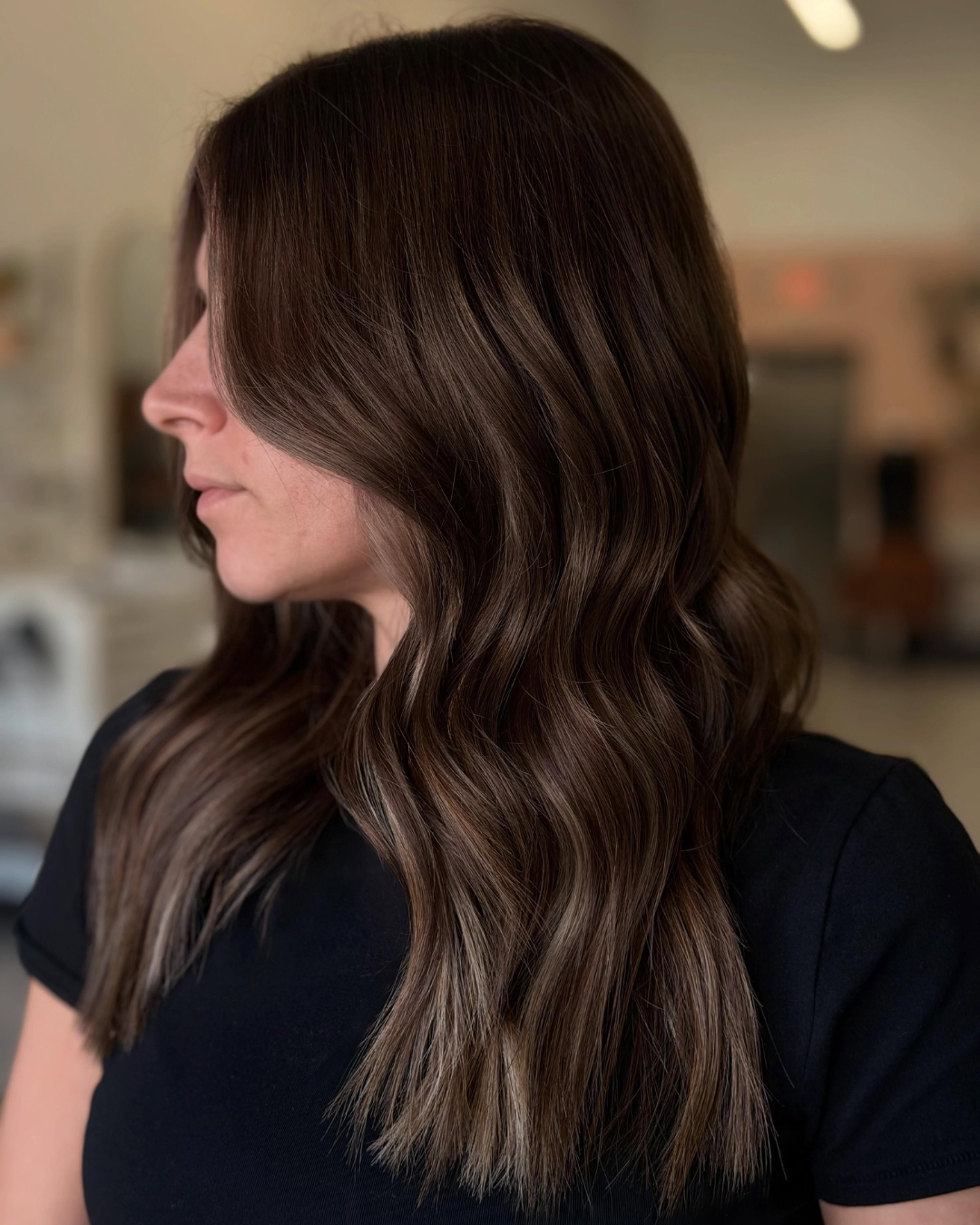 Long dark brown layered hair styled with custom color and extensions by Jessica.