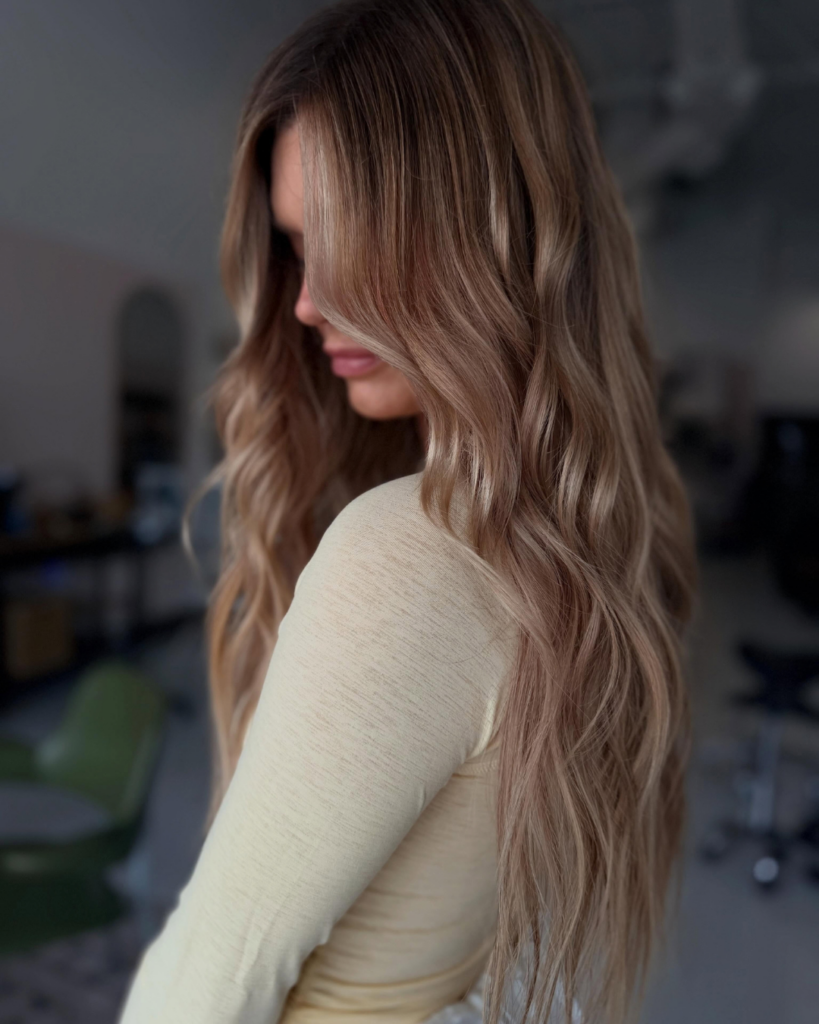 Long blonde hairstyle featuring K-tip extensions and soft waves by Jessica.