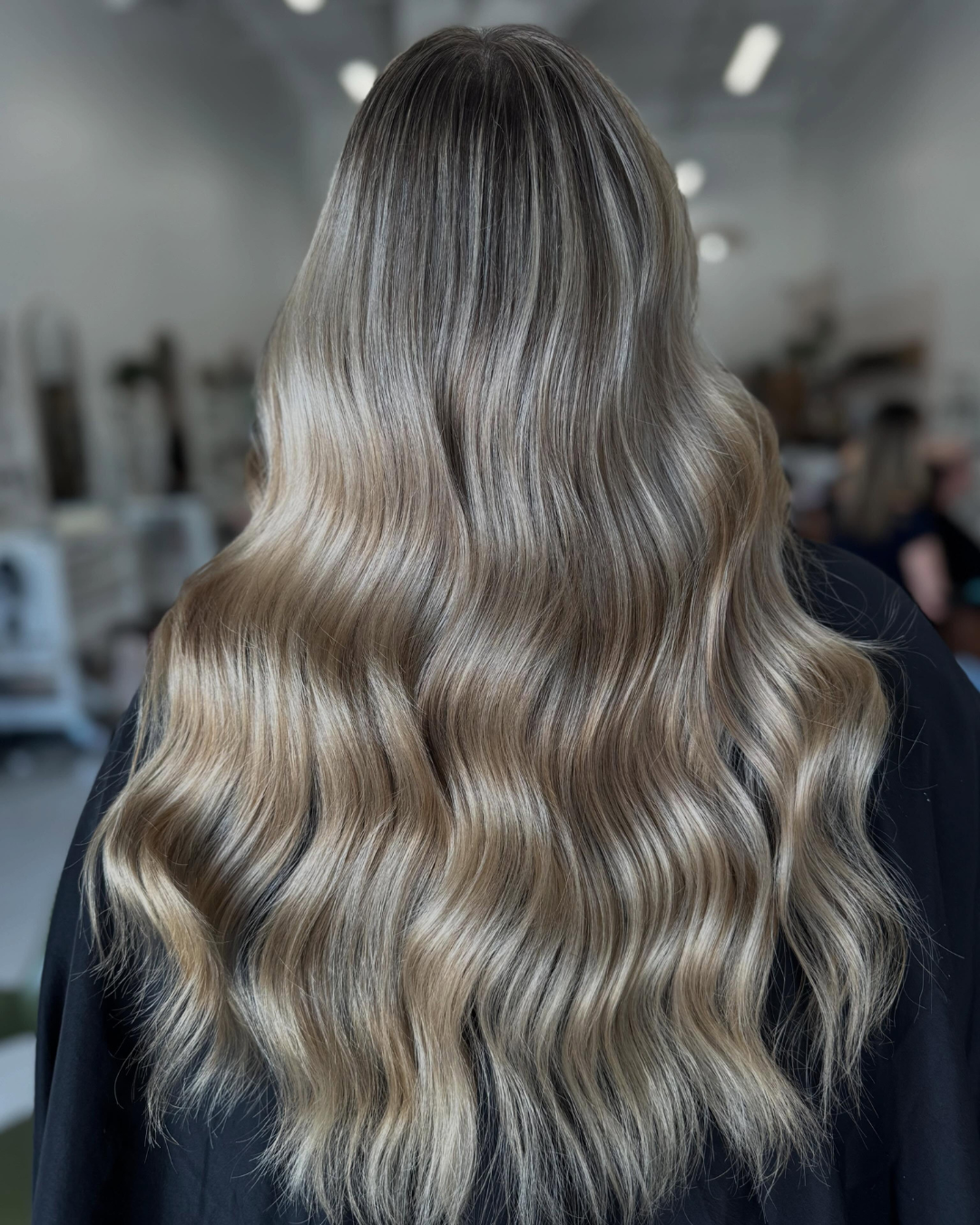 Back view of long, wavy ash blonde and brown dimensional balayage hair.