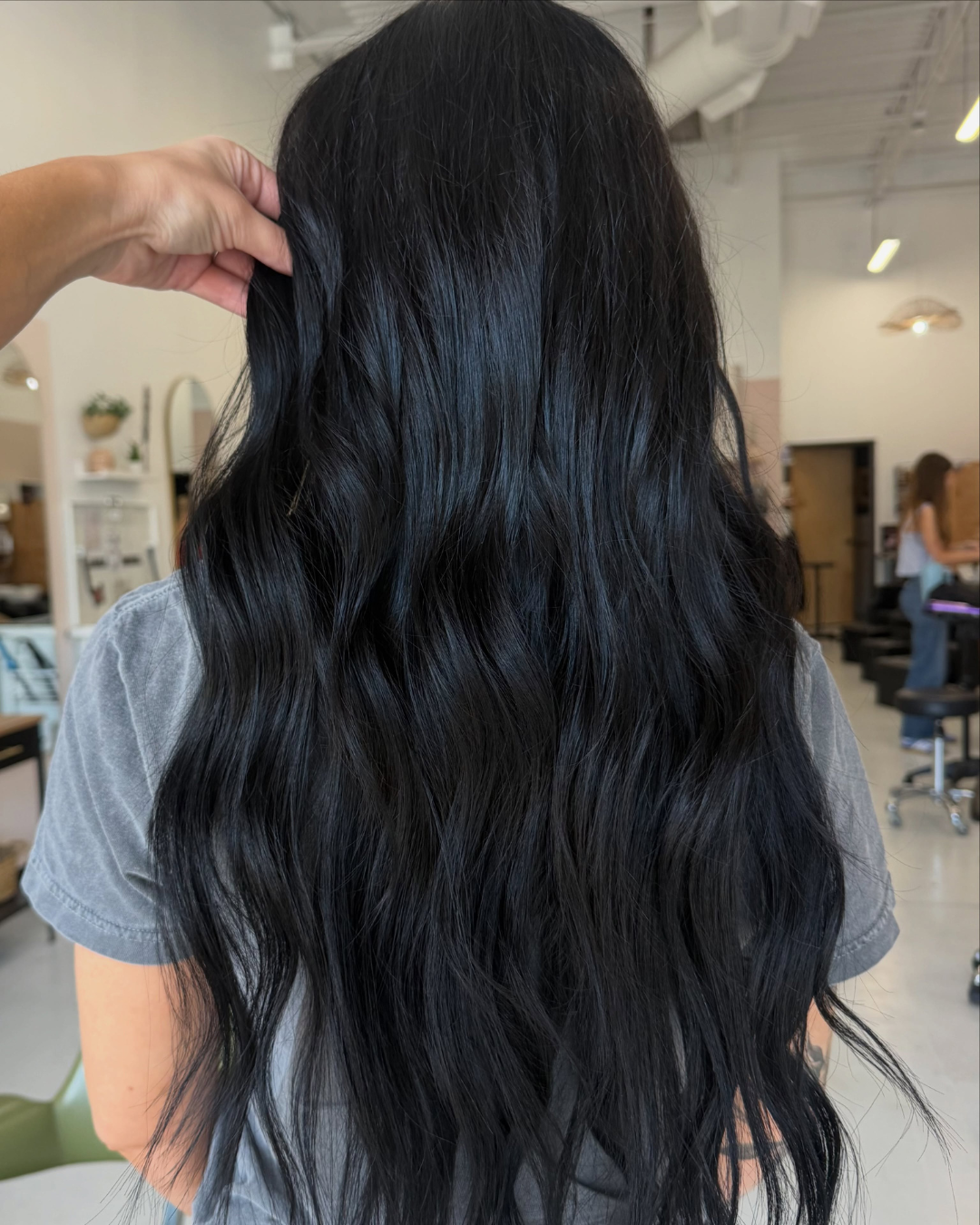 Back view of long wavy dark black hair extensions styled by Abigail.