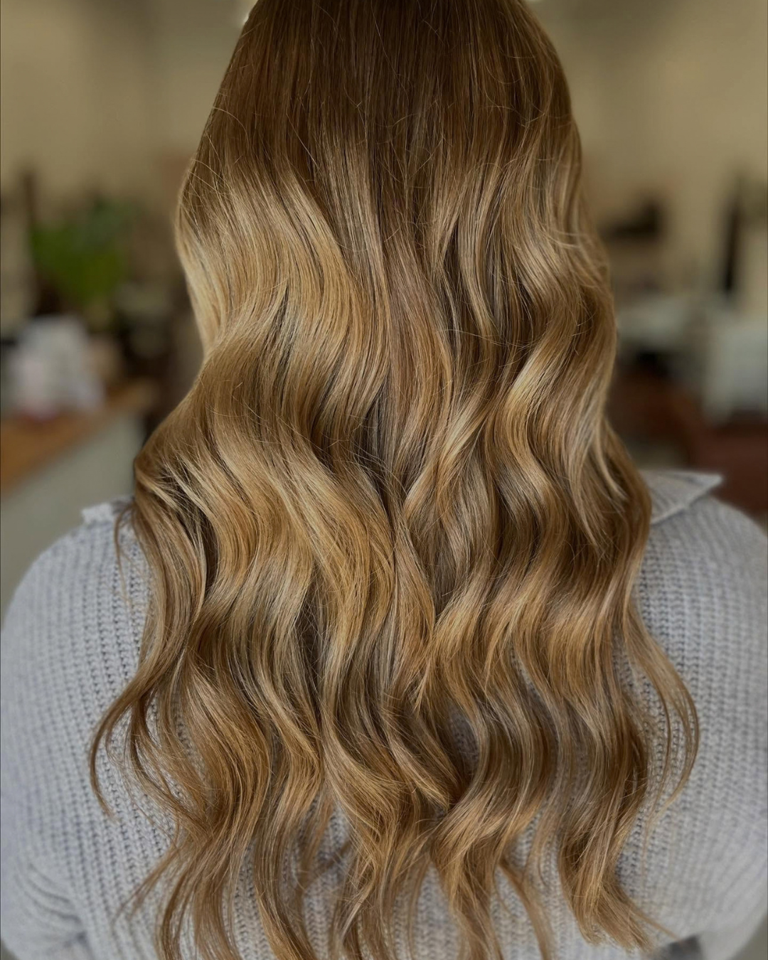 Back view of long, wavy golden blonde balayage hair styling by Ashley.