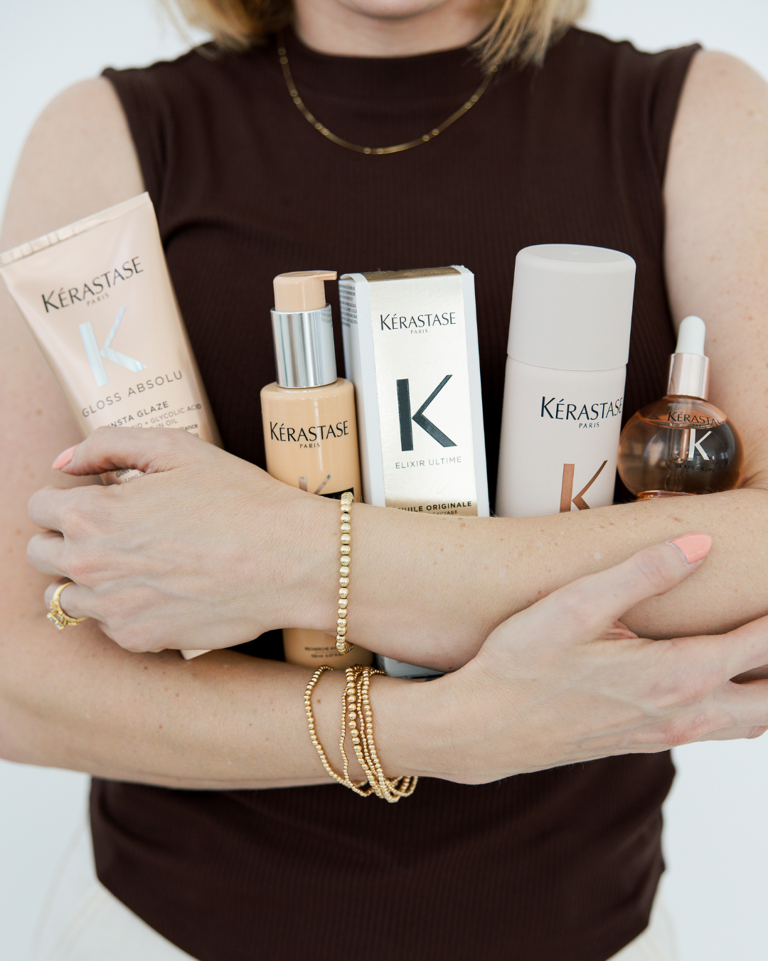 Close-up of a stylist arms displaying a collection of luxury Kerastase hair care products at Fort Worth.
