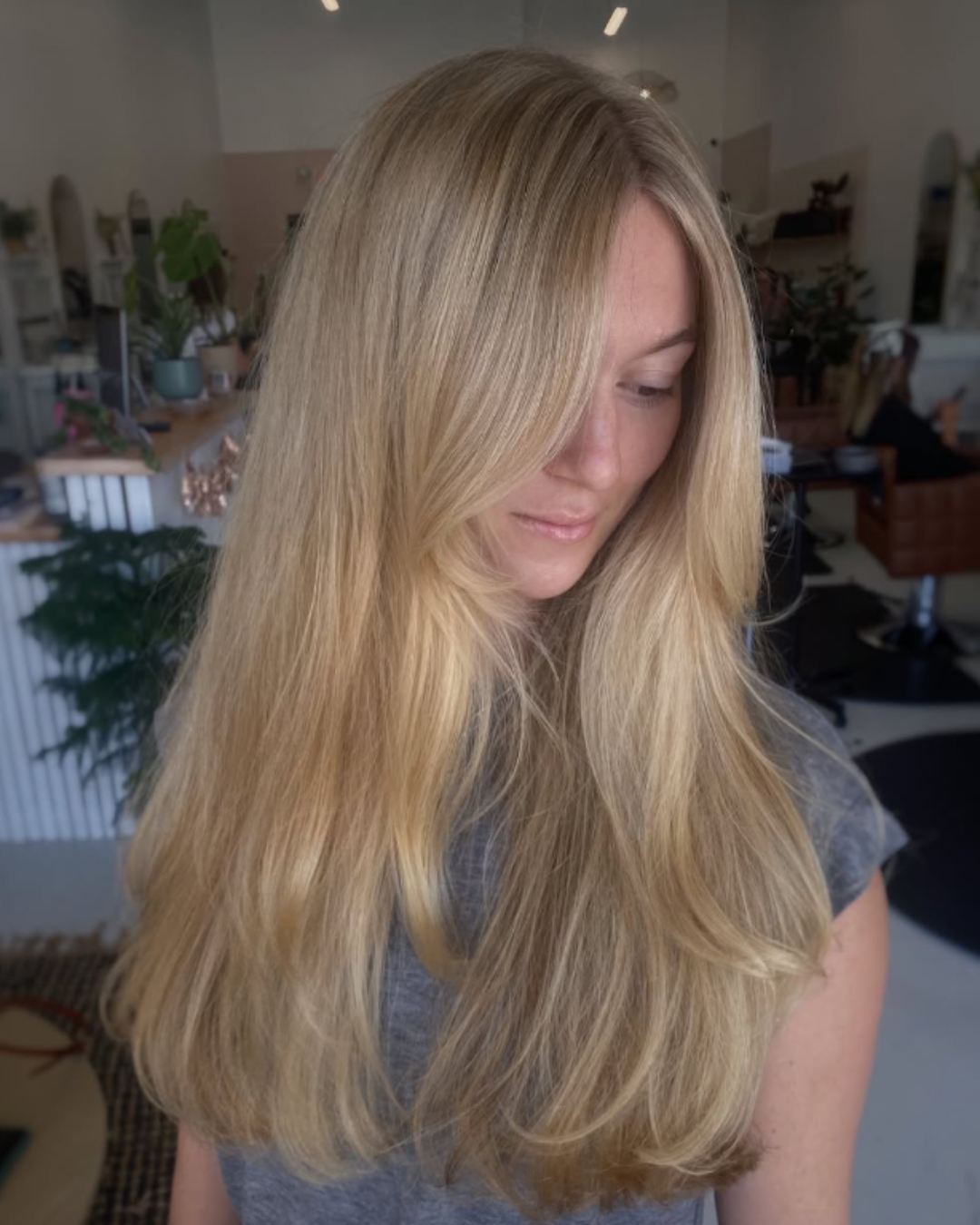Front view of a woman with long, natural blonde hair featuring face-framing layers and soft volume.