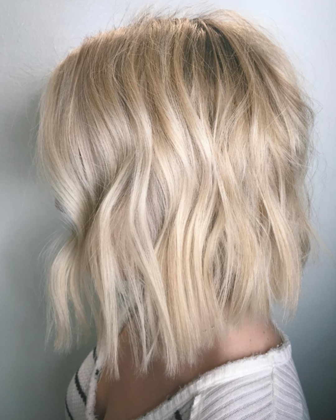 Side view of a textured pearly-blonde short bob haircut with soft, wavy layers.