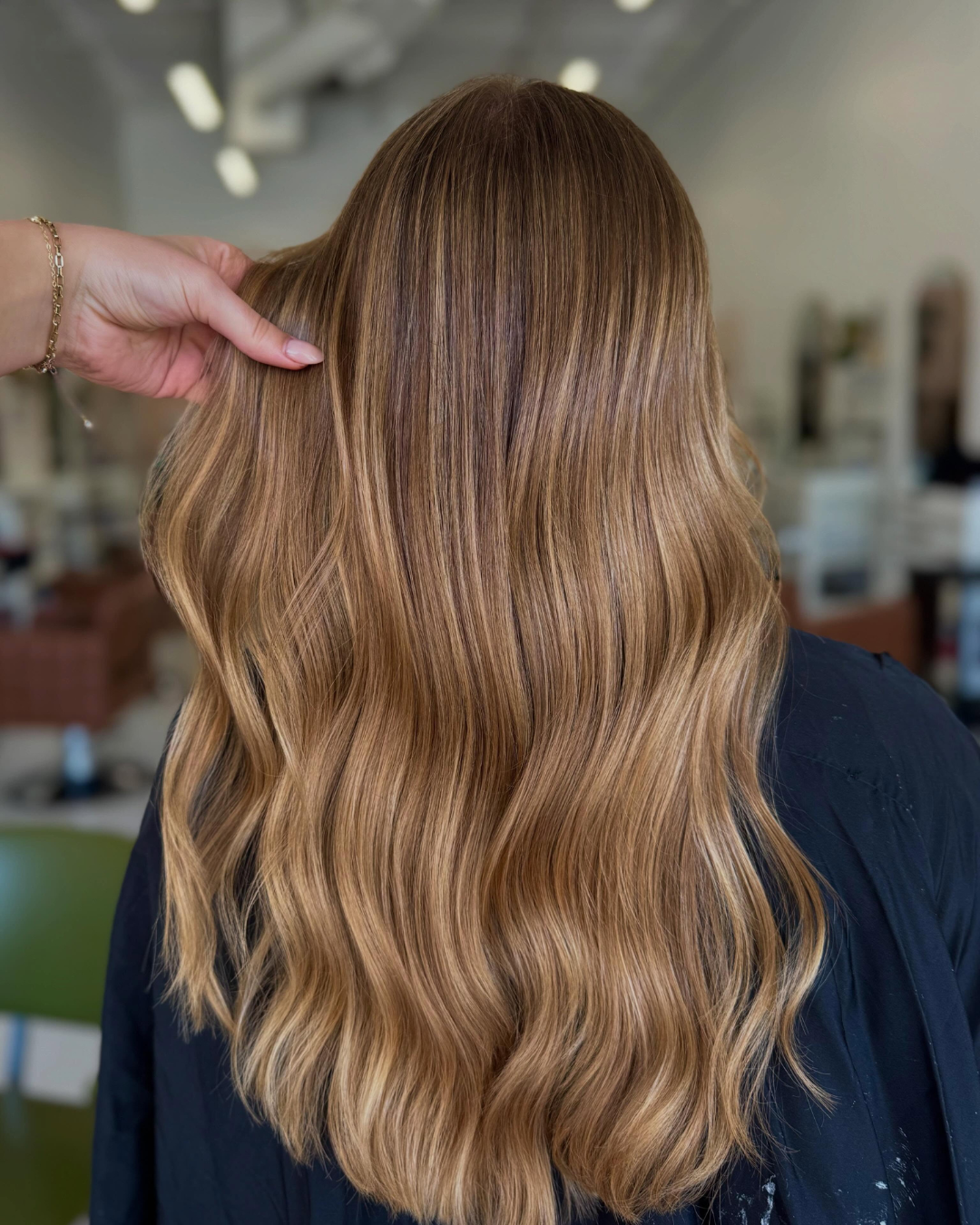 Back view of long strawberry blonde hair with soft waves and highlights.