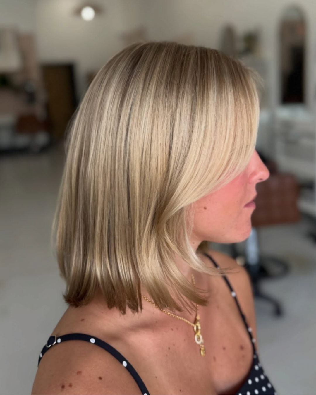 Side view of a medium-length straight summer blonde bob with subtle face-framing layers by Zoe
