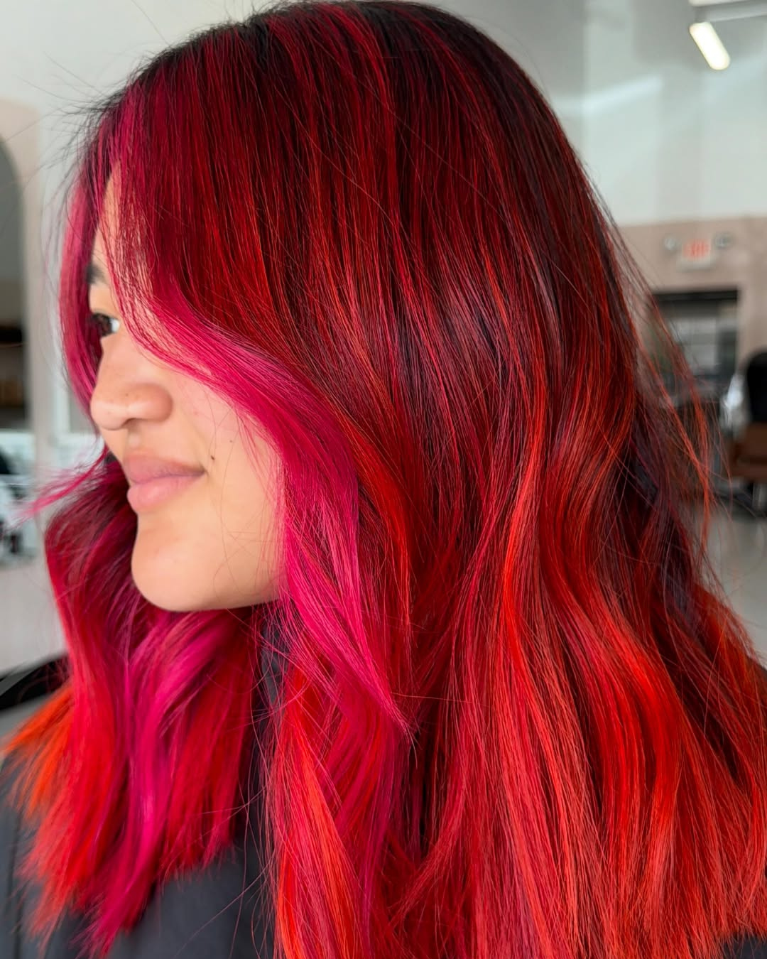 Vivid red to bright orange balayage hair color with face-framing layers by Jessica.
